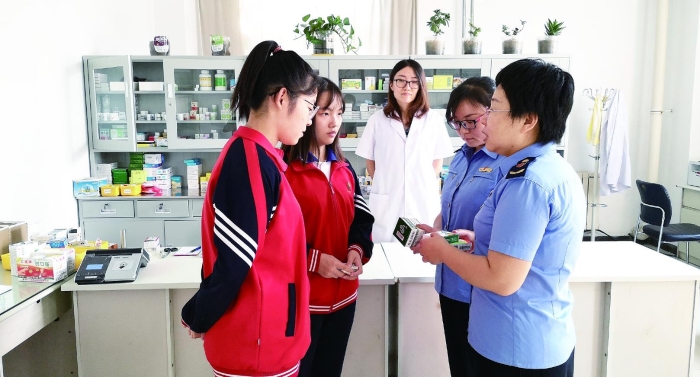 圖為執(zhí)法人員向?qū)W生普及安全用藥知識。