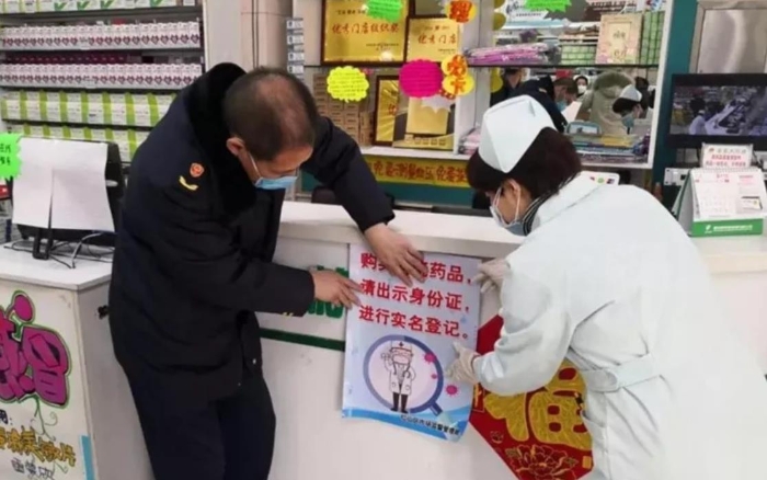 赤峰市紅山區(qū)市場(chǎng)監(jiān)管局監(jiān)管人員正在藥店張貼“實(shí)名登記購(gòu)買退燒藥”宣傳海報(bào)。（赤峰市市場(chǎng)監(jiān)管局供圖）