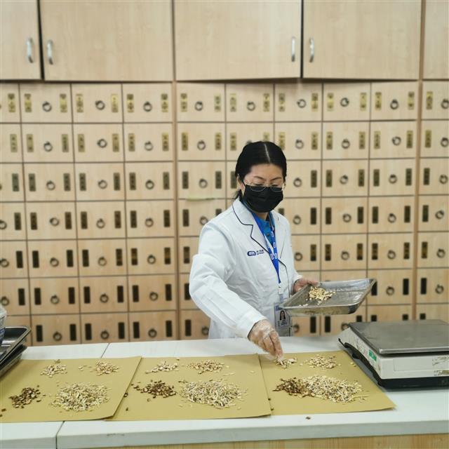 　侯惠鳴為顧客抓藥。