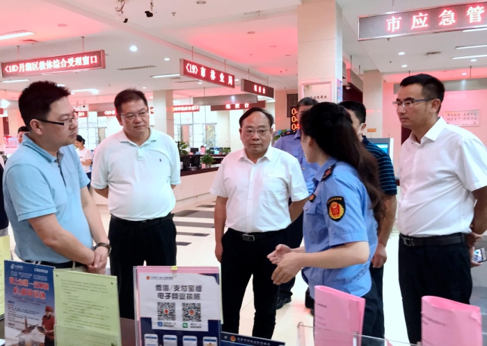 上官新晨（左三）在鷹潭市行政服務(wù)中心詳細(xì)了解“一照含證”改革情況。