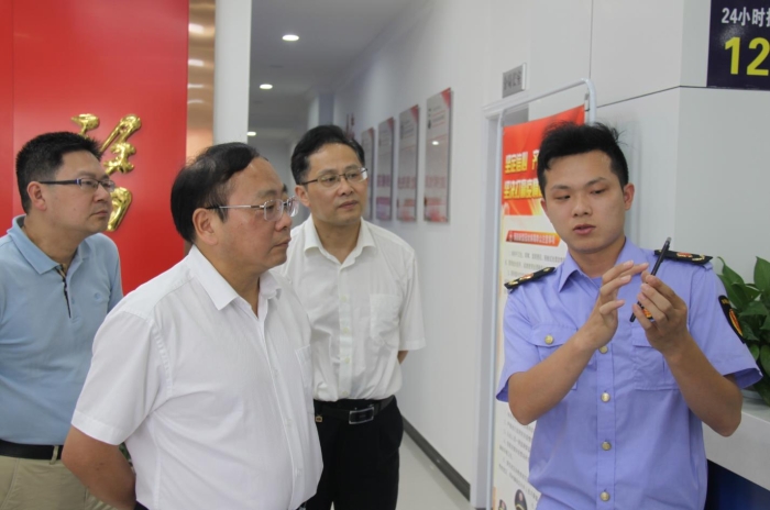 上官新晨（左二）在鷹潭市局東湖分局觀看基層執(zhí)法人員演示如何運(yùn)用智慧市場(chǎng)監(jiān)管網(wǎng)格化管理平臺(tái)開展監(jiān)督檢查工作等情況。