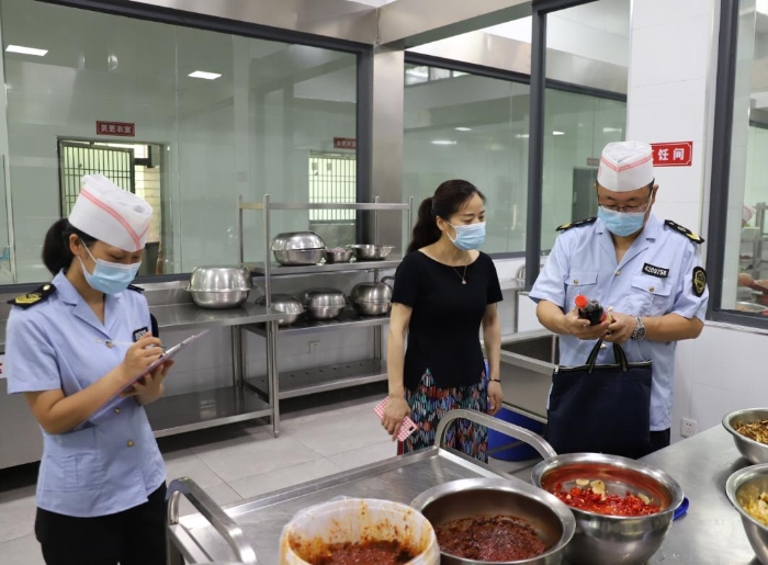 圖為執(zhí)法人員在檢查學(xué)校食堂加工制作情況。