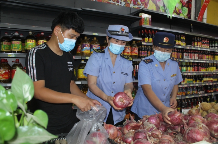 圖為執(zhí)法人員和檢測機(jī)構(gòu)工作人員抽取蔬菜樣品送檢。