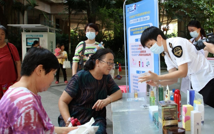 圖為檢驗人員在為群眾現(xiàn)場講解辨別假冒偽劣化妝品的方法。（程奇 攝）