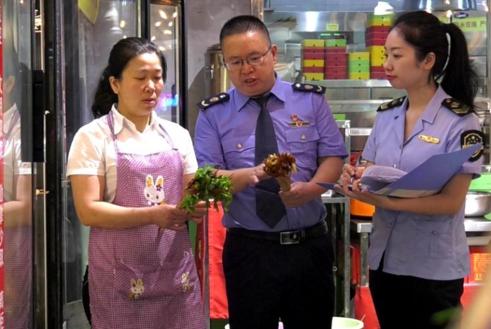 圖為執(zhí)法人員在一火鍋店檢查火鍋食品原輔材料進(jìn)貨情況。