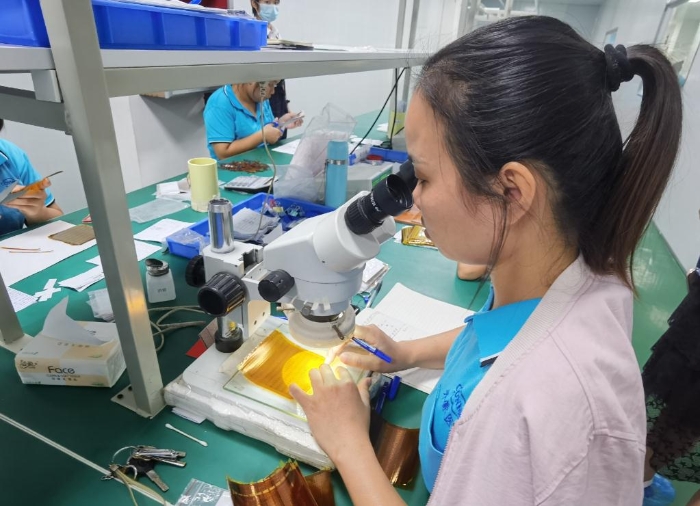 開蒙醫(yī)療員工在用顯微鏡檢查人體成分分析儀芯片上的箔片集成電路是否有缺陷。
