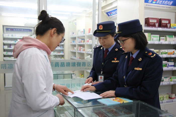 圖為執(zhí)法人員在佰藥之家大藥房發(fā)放安全用藥科普手冊。