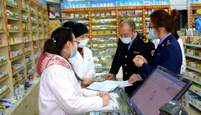 圖為執(zhí)法人員在一家藥店檢查防疫物資銷售記錄。