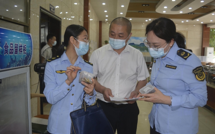 圖為執(zhí)法人員在食品檢查留樣情況。