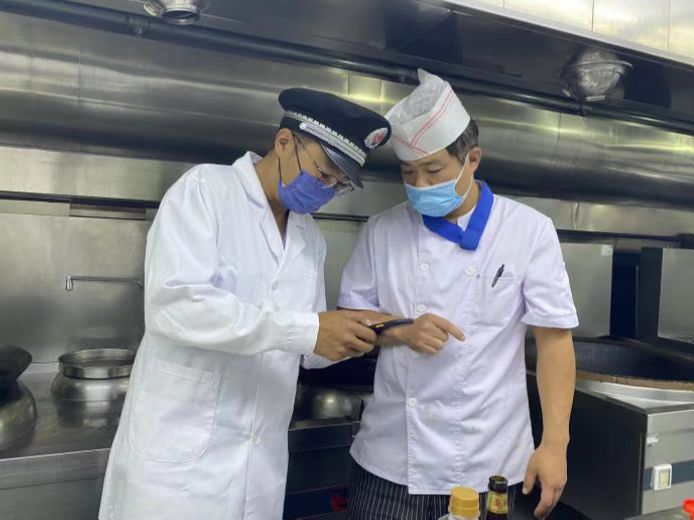 圖為海淀區(qū)市場監(jiān)管局執(zhí)法人員檢查學(xué)校食堂食品安全。