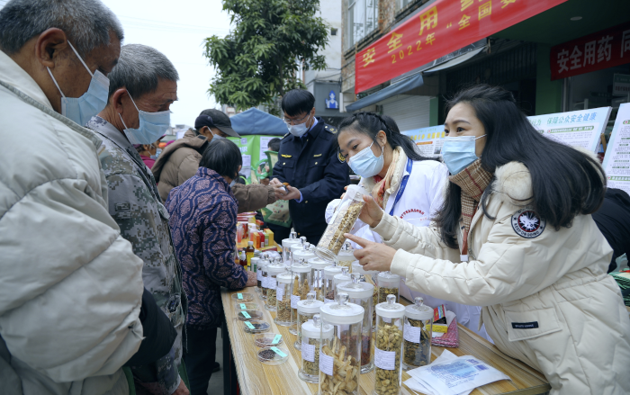 圖為工作人員現(xiàn)場向群眾講解常用中藥材的鑒別知識，普及藥品安全相關(guān)法律法規(guī)。