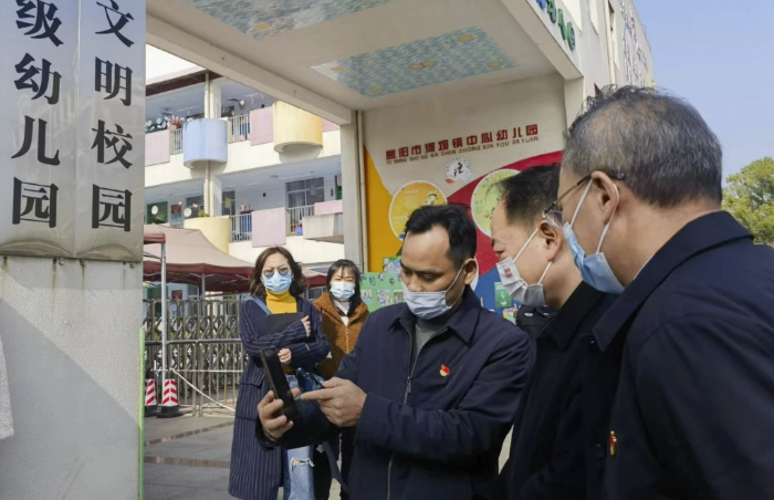 圖為樂(lè)運(yùn)成（右二）通過(guò)手機(jī)客戶端查看大通湖區(qū)第一實(shí)驗(yàn)幼兒園廚房實(shí)時(shí)視頻。
