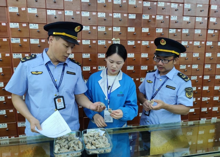 圖為執(zhí)法人員在一零售藥店檢查中藥飲片質(zhì)量情況。