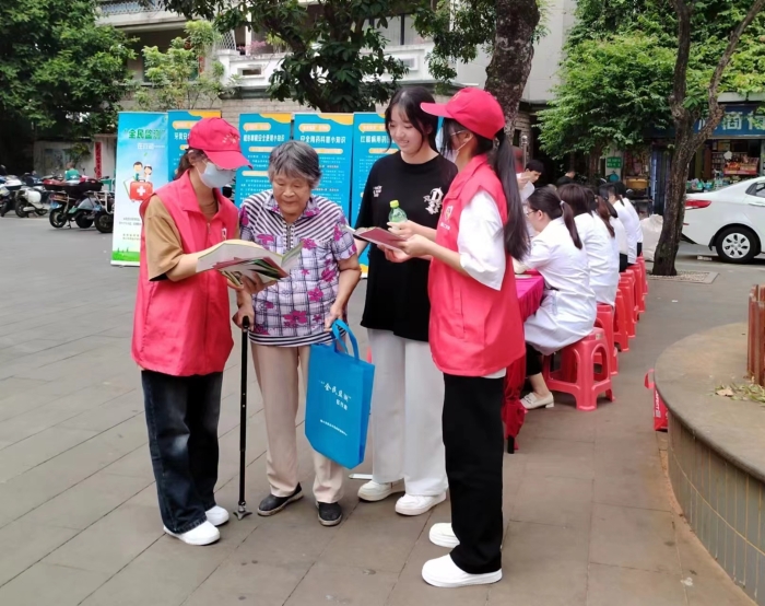 圖為工作人員向過往居民發(fā)放“全民監(jiān)測(cè)”科普宣傳資料。