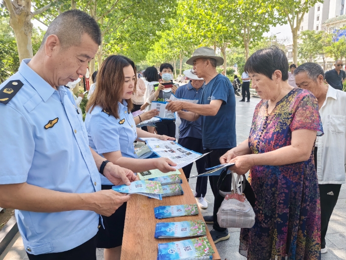 圖為工作人員向群眾發(fā)放禁毒宣傳手冊。